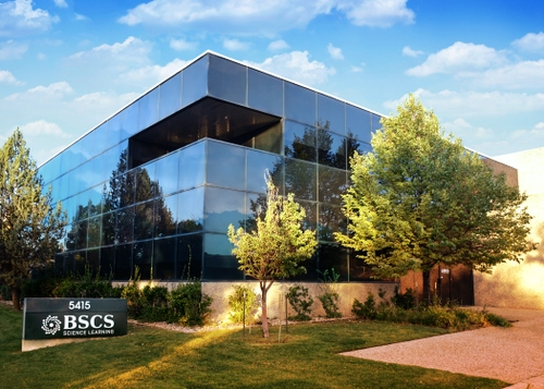 Building with lots of windows, BSCS sign and trees in front of it.