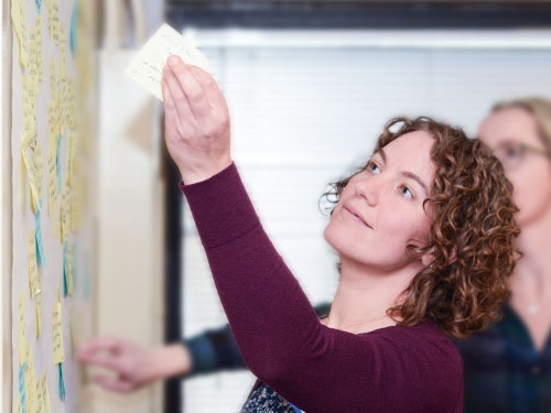 Woman putting Post-it Notes on wall.