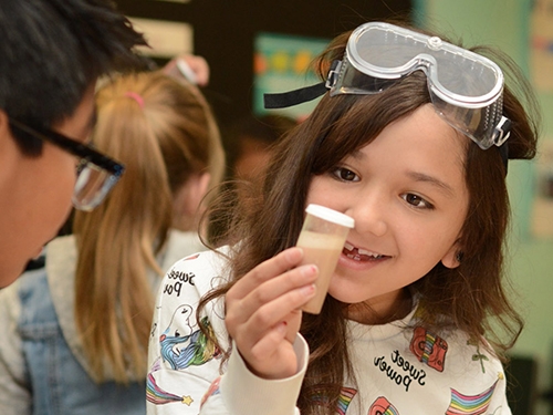 Elementary school student examining a sample of sand.